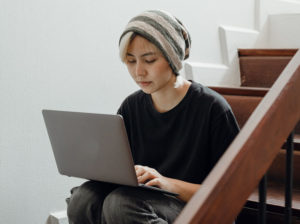 Young-female-working-on-laptop-sitting-on-steps